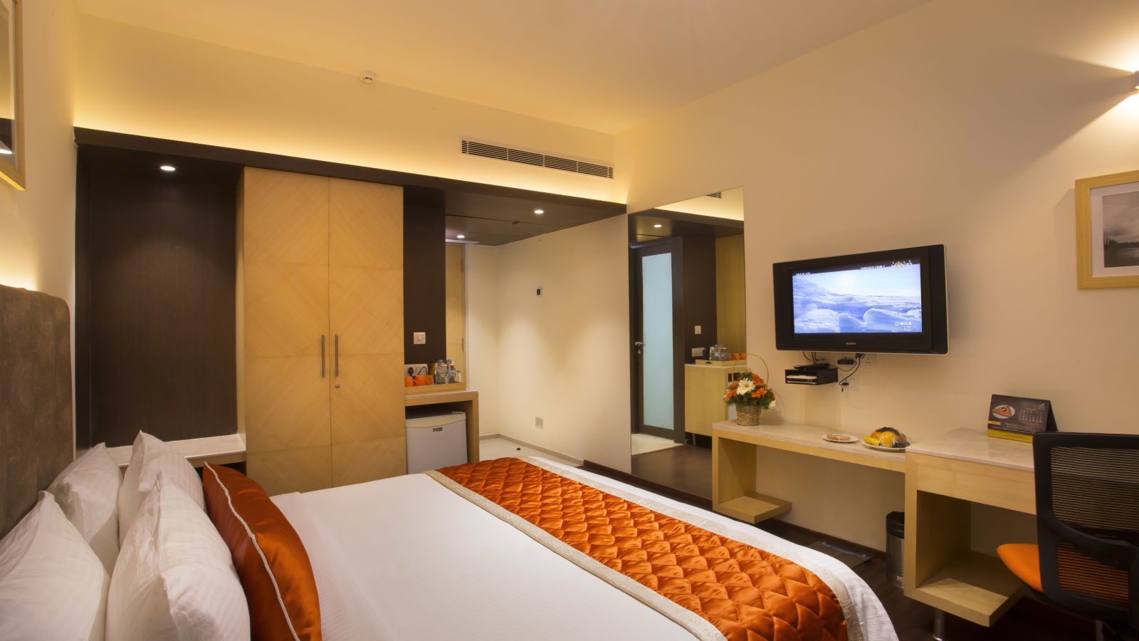 A comfortable hotel room with modern amenities, a large bed, a TV and a work desk with a chair - Hotel Langford Keys by TGI, Shanti Nagar