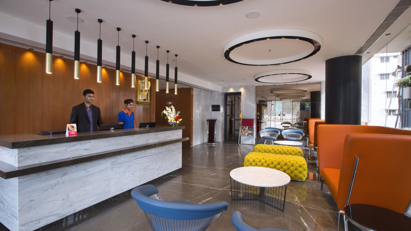 A modern hotel reception area with bright orange and yellow seating, a dark wooden front desk and pendant lights - Hotel Southend by TGI - Bommasandra, Bangalore