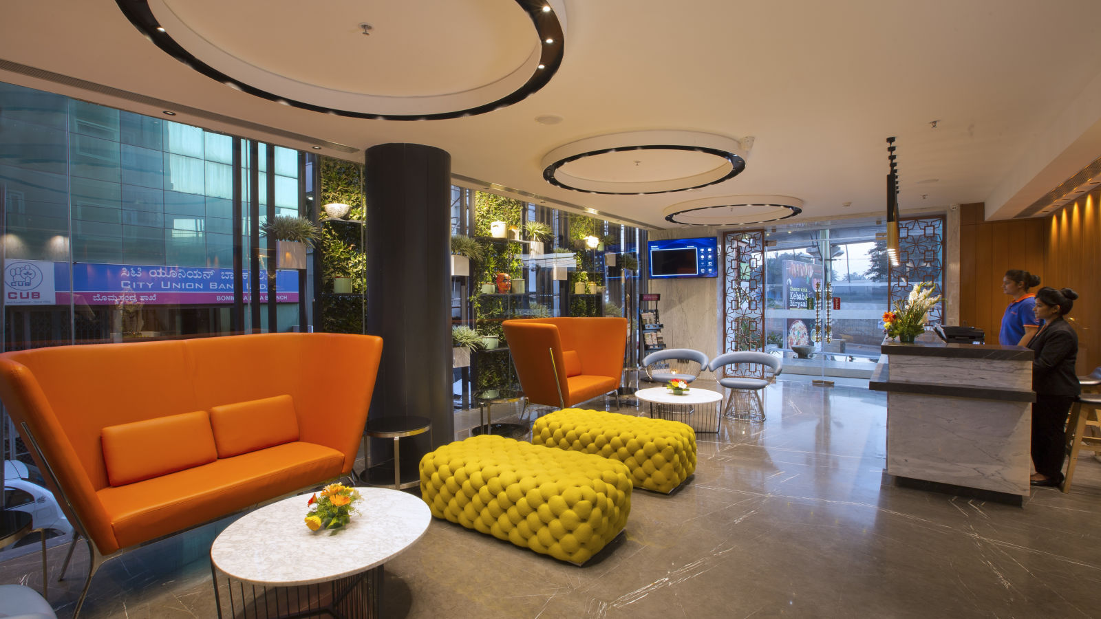 A modern hotel lobby with vibrant orange and yellow seating, circular lighting fixtures and a reception desk - Hotel Southend by TGI - Bommasandra, Bangalore