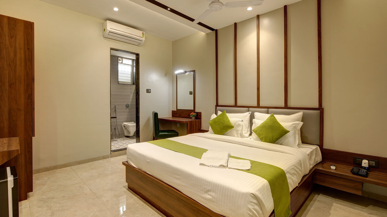 A double bed with an ac wall mounted next to it inside Classic AC Room - Fortune House, Magarpatta