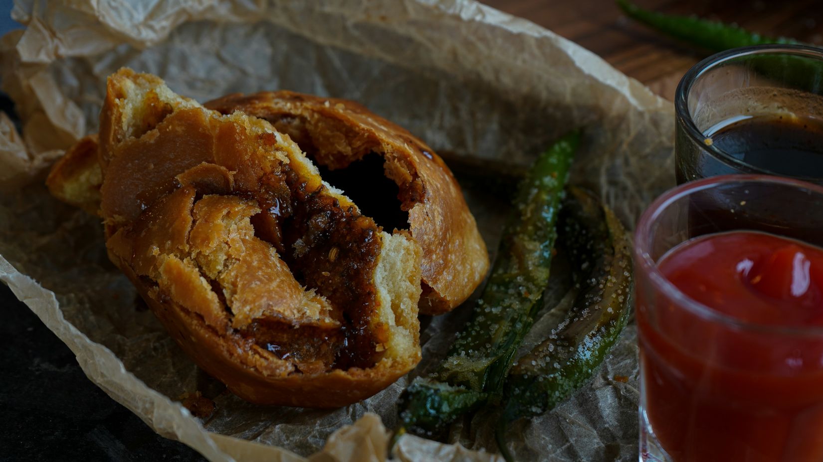 a close up shot of kachori with dips on the side and chutney next to it