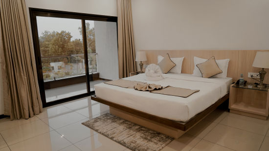 Pride Ranakpur Resort Convention Centre - interior view of the super deluxe room containing a king size bed and cream coloured decor