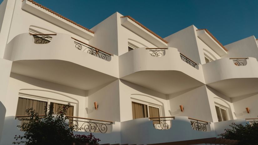 A close-up of a white Mediterranean-style villa with decorative iron railings and terracotta roof tiles