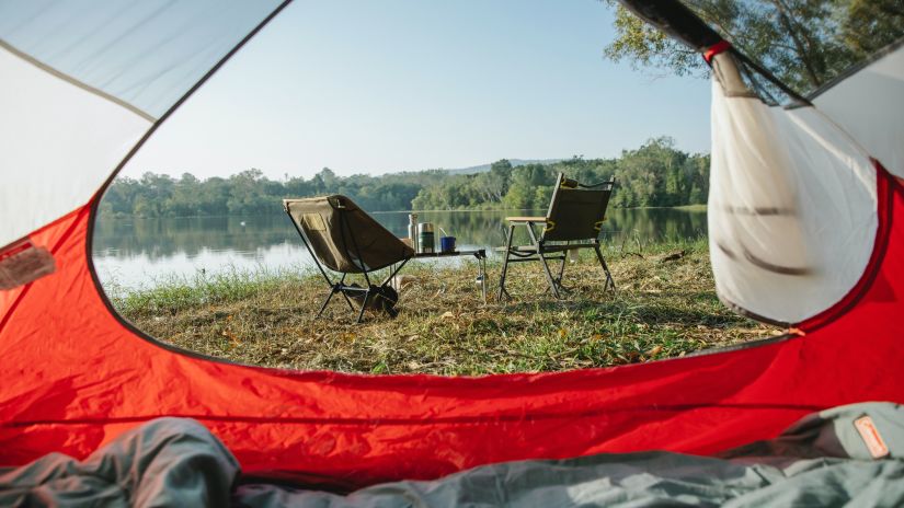 From inside the tent, two camping chairs sit next to Pawna lake, suggesting a quiet morning. - -Fort JadhavGADH