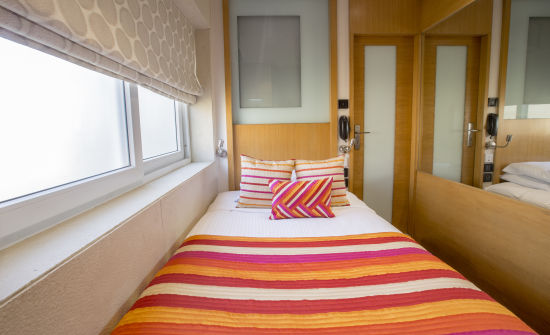 alt-text room with single bed and wooden furnishing at hotel bawa continental