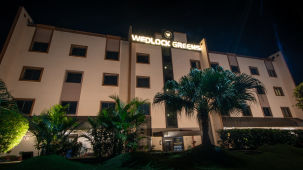 The facade of the hotel surrounded by palm trees at night