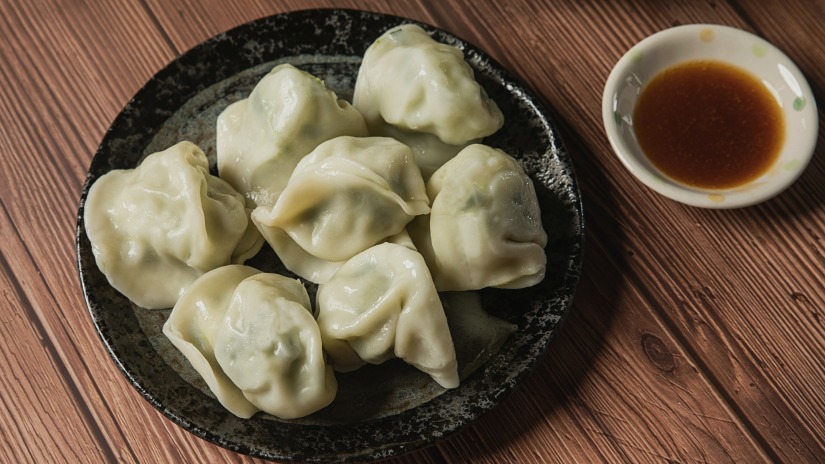 a plate served with steamed dumplings with a sauce placed by its side