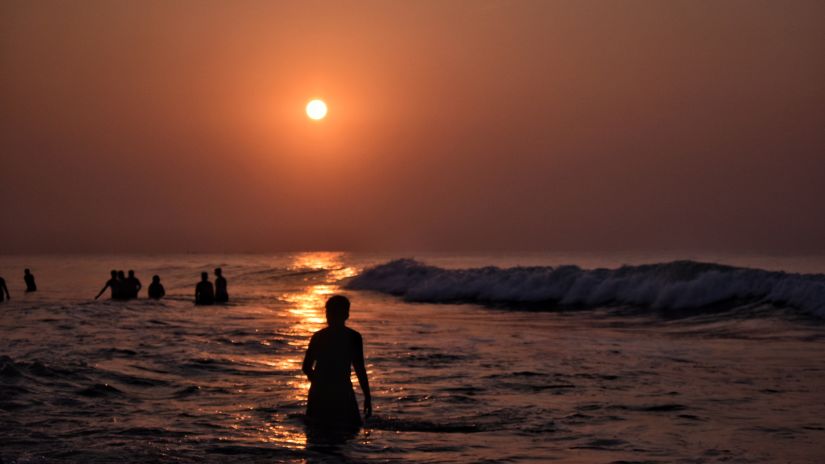 a man taking a dip in the ocean during sunrise