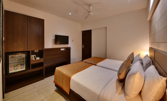 alt-text twin bed with tv mounted and wardrobe next to it in the twin room at Click hotel Vadodara