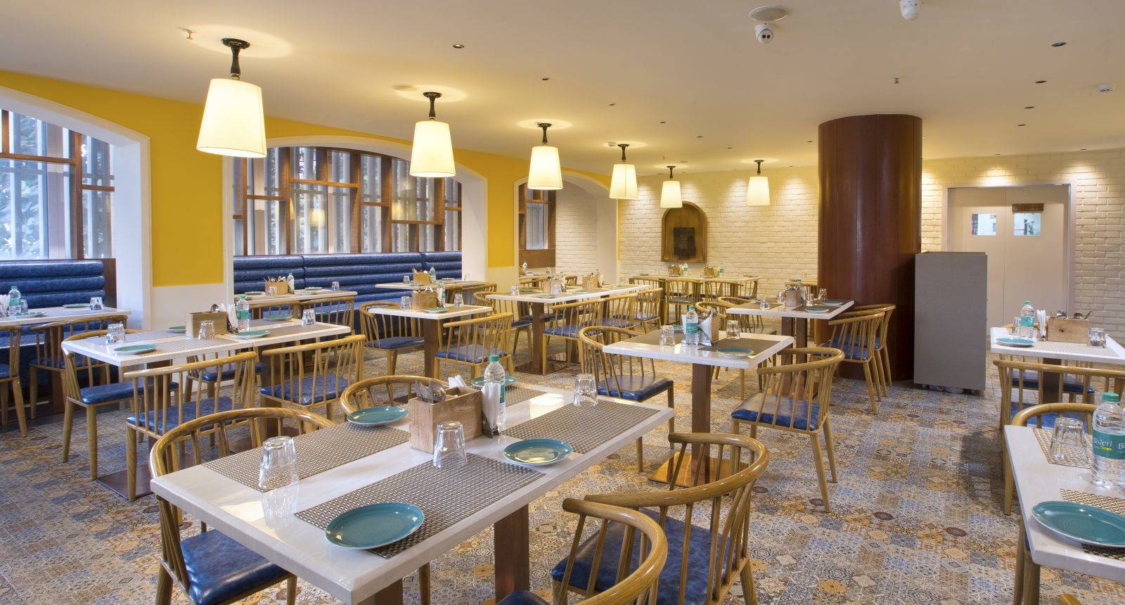 A spacious and brightly lit restaurant with wooden chairs, patterned tile floor and large windows - Hotel Southend by TGI - Bommasandra, Bangalore