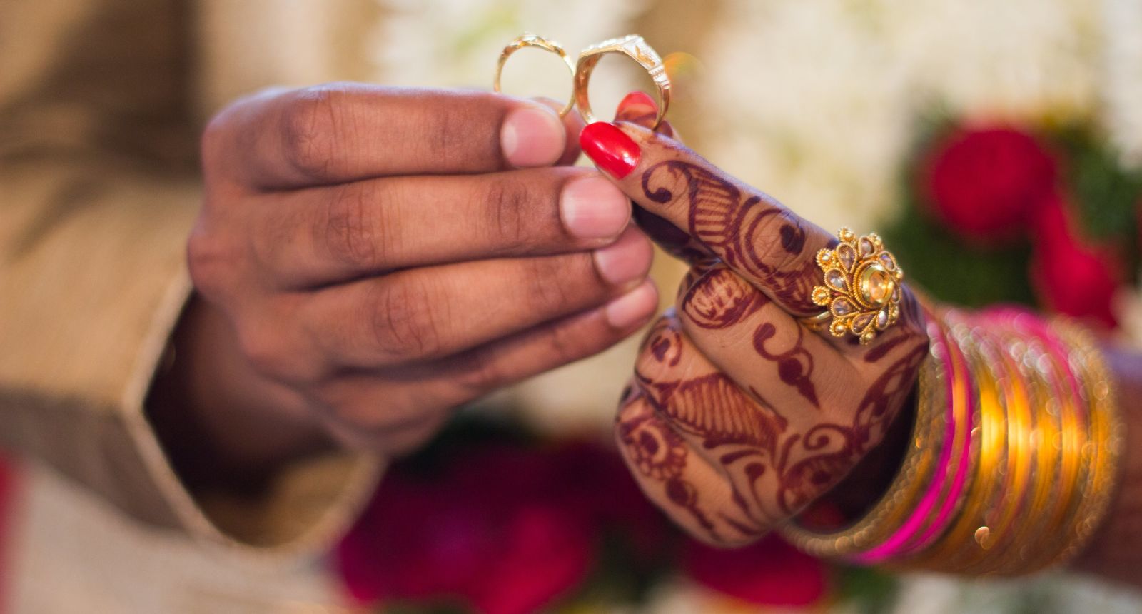A close-up of a people's hands exchanging wedding rings