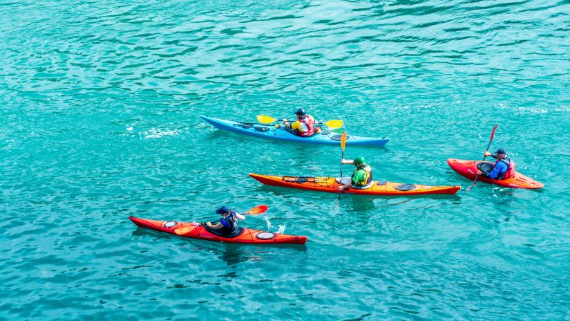 A group of people kayaking in blue azure waters 