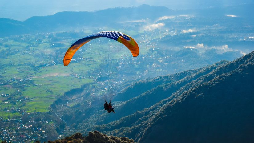 Digantaa Resort - a person paragliding amid mountains