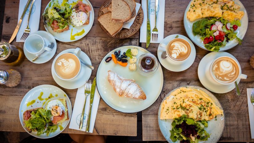 A table with a spread of breakfast items with hot beverages