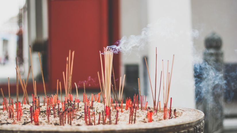 incense being burned in a bowl filled with sand inside a temple