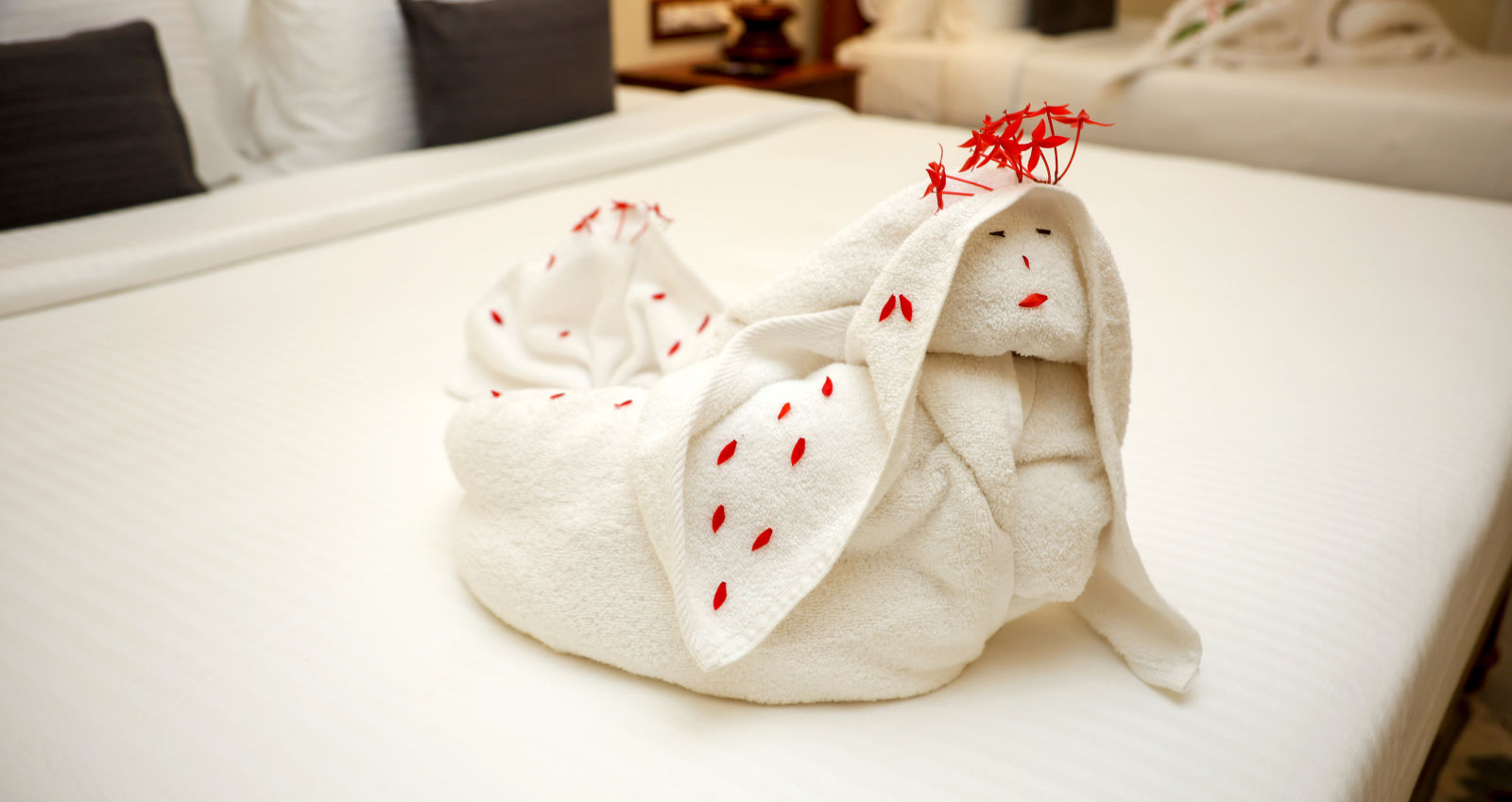 A bed decorate with towels and few flower petals  | Mango HIll La Serene, Ponicherry