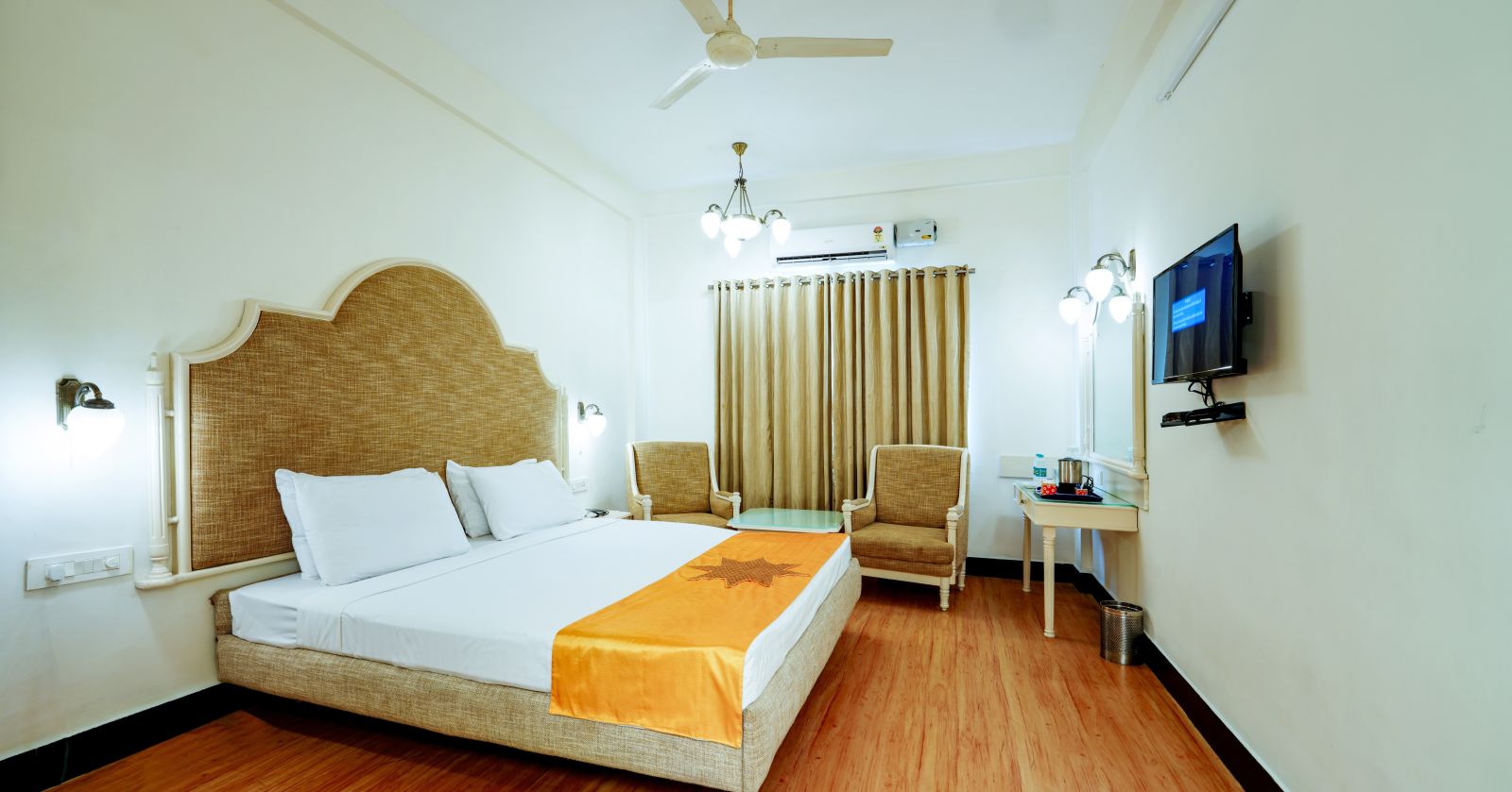 The hotel room from a different angle, emphasizing the space and the wooden floor. - Greens Inn - Cozy Accommodations