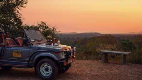 a safari jeep parked next to a bench of a view point with different hues in the sky after the sunset - Chunda Shikar Oudi, Udaipur