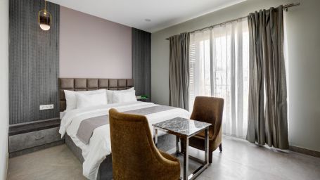 Grey themed Deluxe room with king size bed and brown chairs - The White Moon