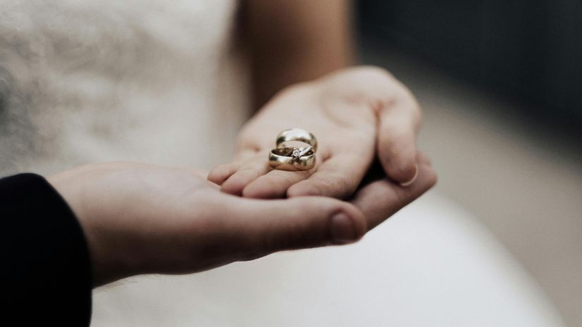 A couple holding  a wedding ring with hand on hand