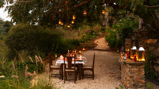 a table for four set up next on a pathway with forest cover surrounding it - Chunda Shikar Oudi, Udaipur