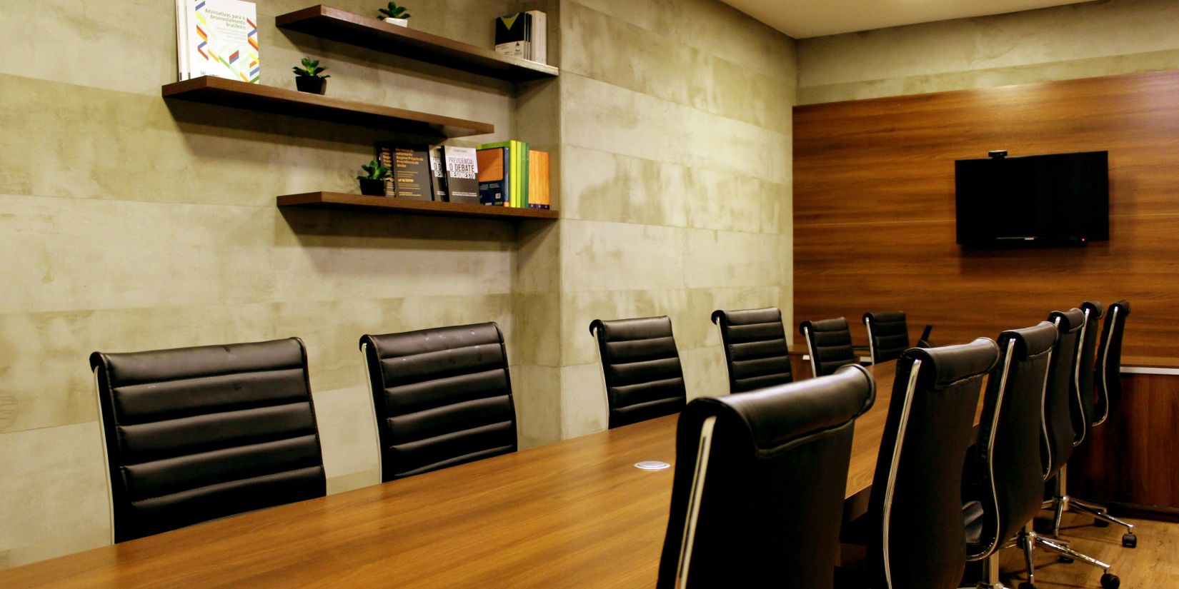 The interiors of a meeting room with a wooden table and black seats