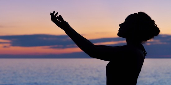 silhouette of woman doing yoga by the beach