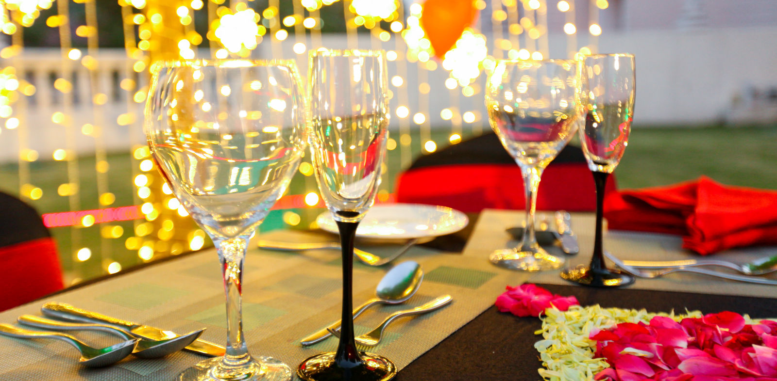 glasses set on a table with plates, cutlery and decoratations in the backdrop 