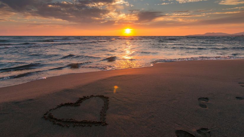 Heart drawn on a beach at sunset