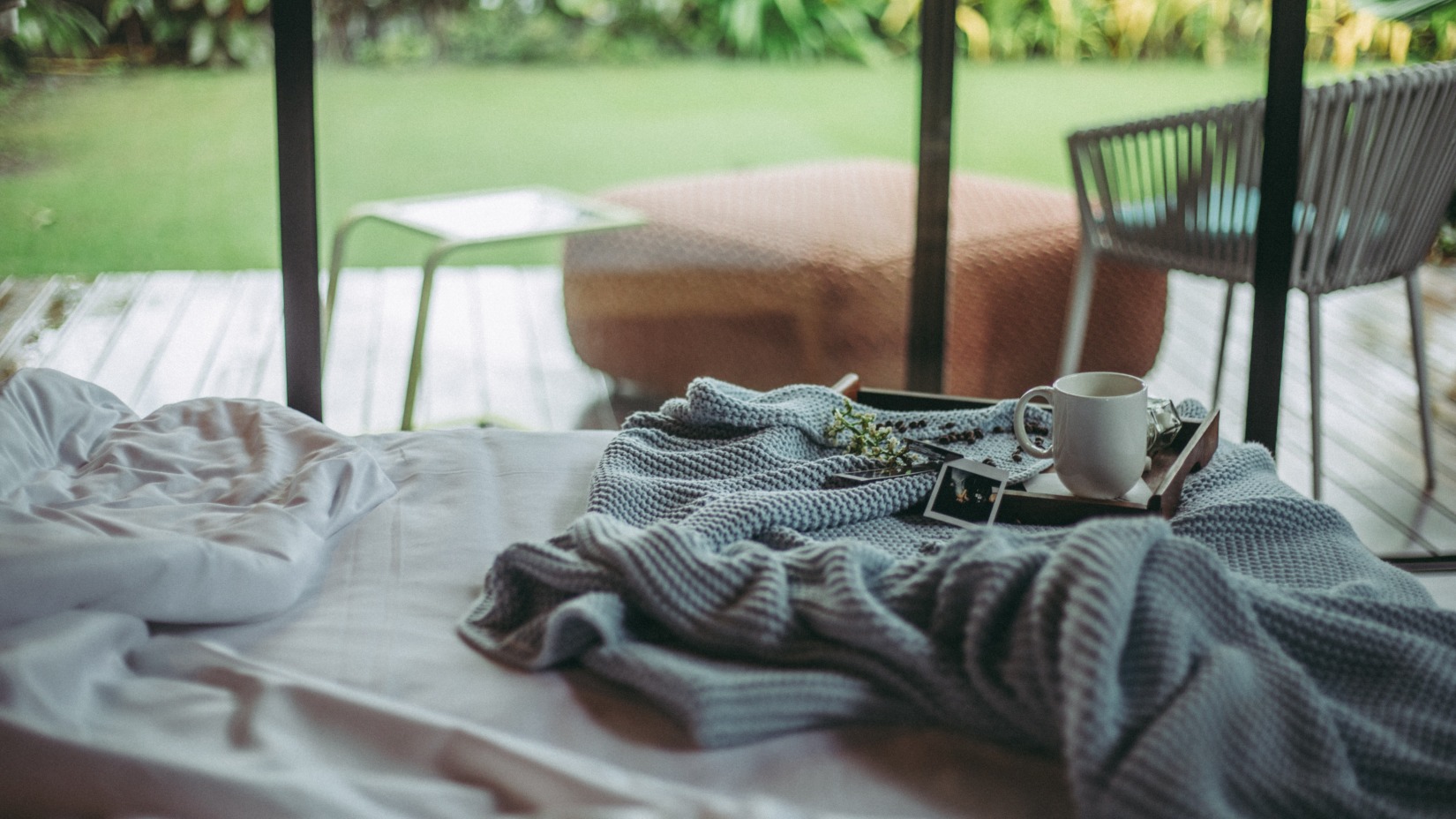 A bed with a Blanket & Hot Chocolate next to a large window