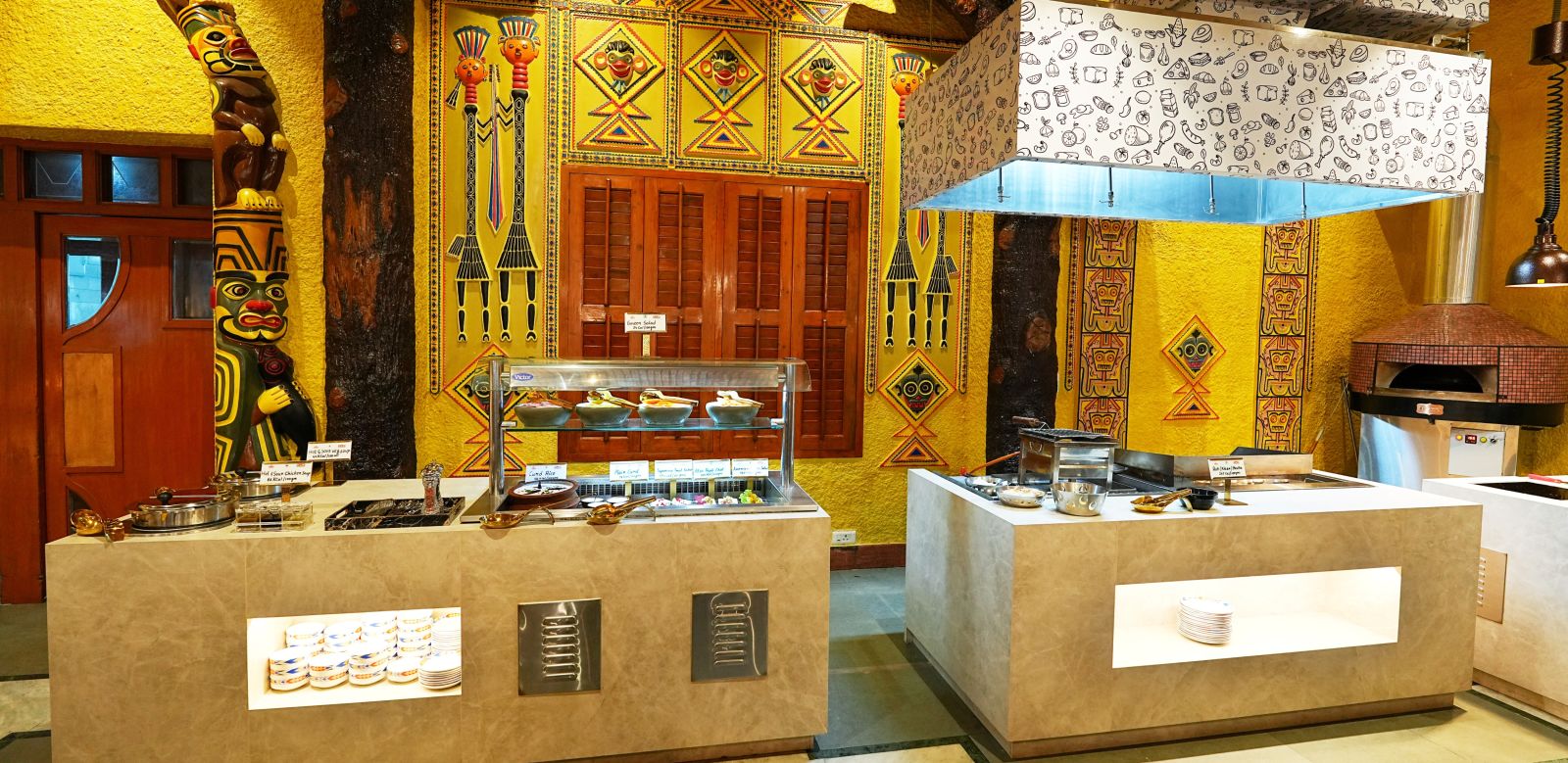 A buffet area with traditional design elements, wood carvings, and ambient lighting. - Tara - Comfort Hotel