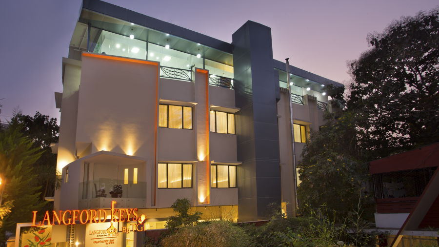 The exterior entrance of Langford Keys Hotel showing the signboard with reflective windows and modern architecture at dusk - Hotel Langford Keys by TGI, Shanti Nagar