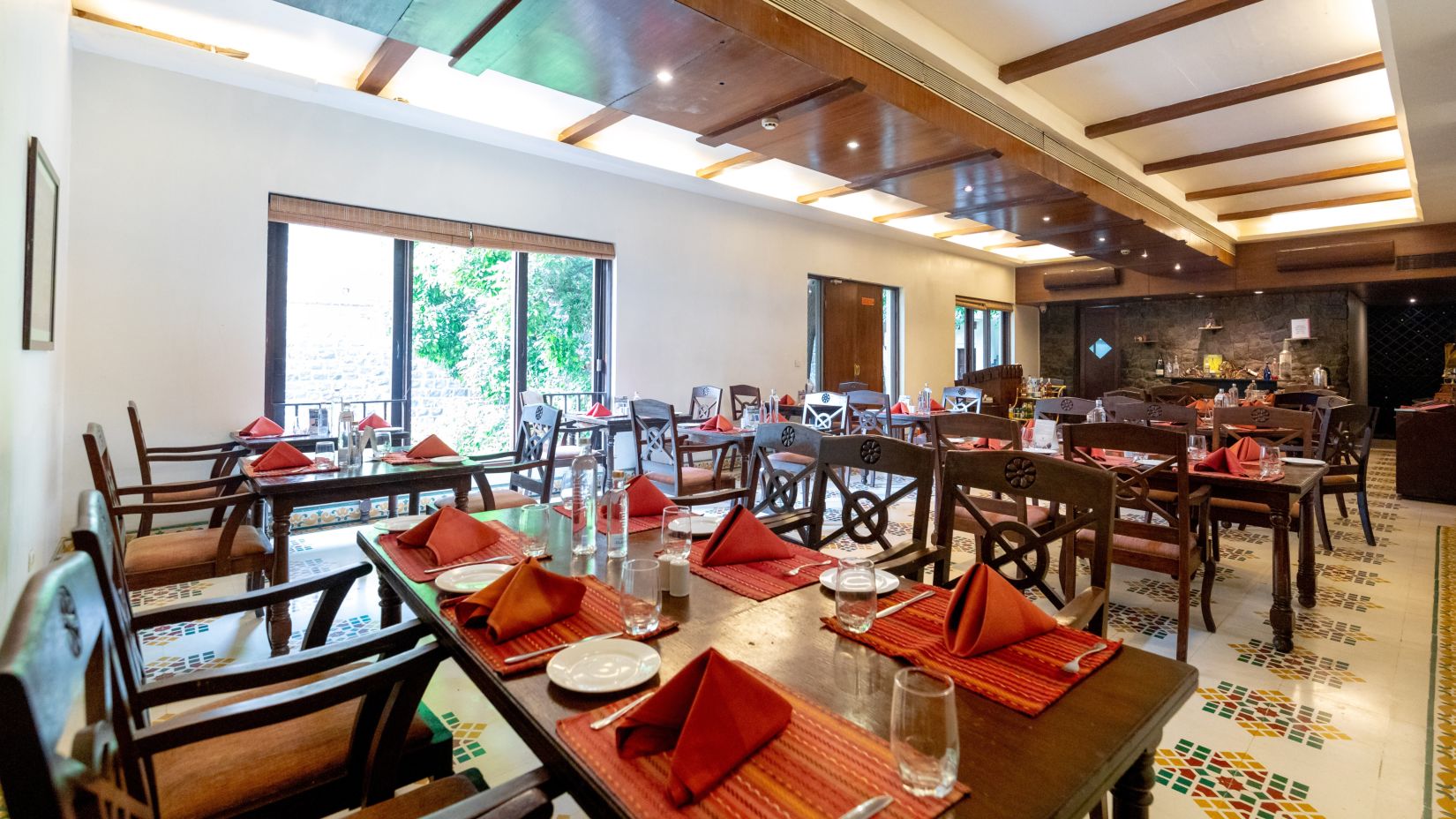  A spacious and well-lit restaurant with modern wooden furniture, large windows, and a tiled floor. Fort JadhavGADH