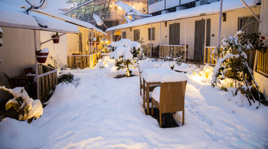 alt-text a view of cottage with dining arrangement covered in snow covered at The Tattva Boutique Resort, Joshimath