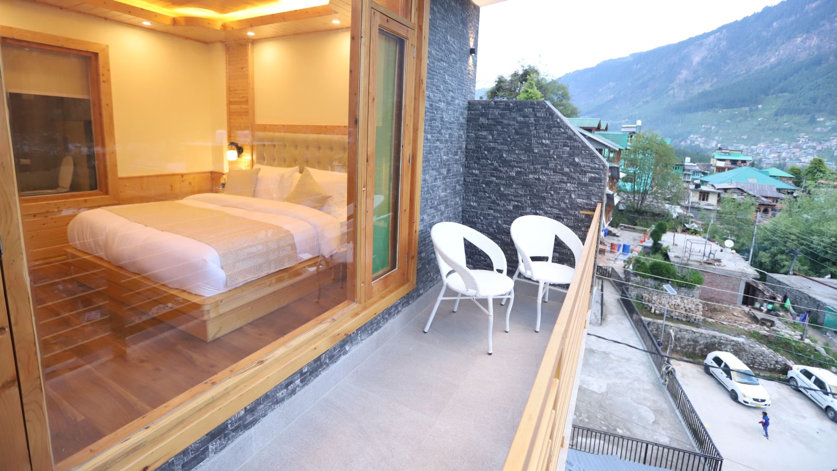 exterior view of the premium room balcony with 2 chairs and a beautiful location as the backdrop - Golden Wood Manali By Rosetum
