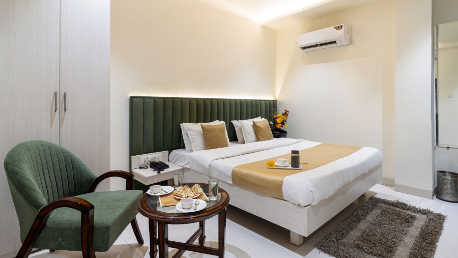 A sofa and a double bed at Deluxe Room at Meghdoot Hotel