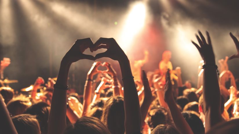 a group of people with their hands up in the air enjoying at a party with spotlights on them in Goa