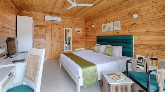 A side view of the cosy bedroom with wooden furnished cosy bed, chair, table Aralea Beach Resort By Stone Wood, Morjim