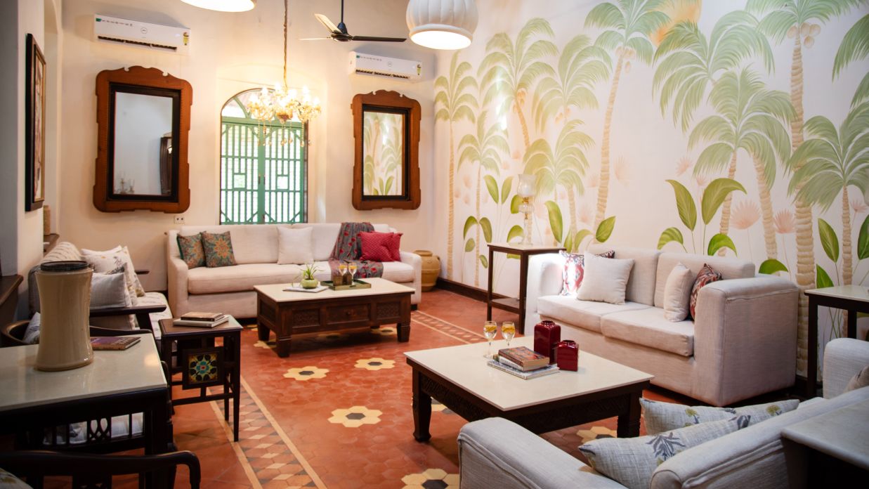 white room with tables and couches with green trees drawn on the walls  @ Lamrin Ucassaim Hotel, Goa