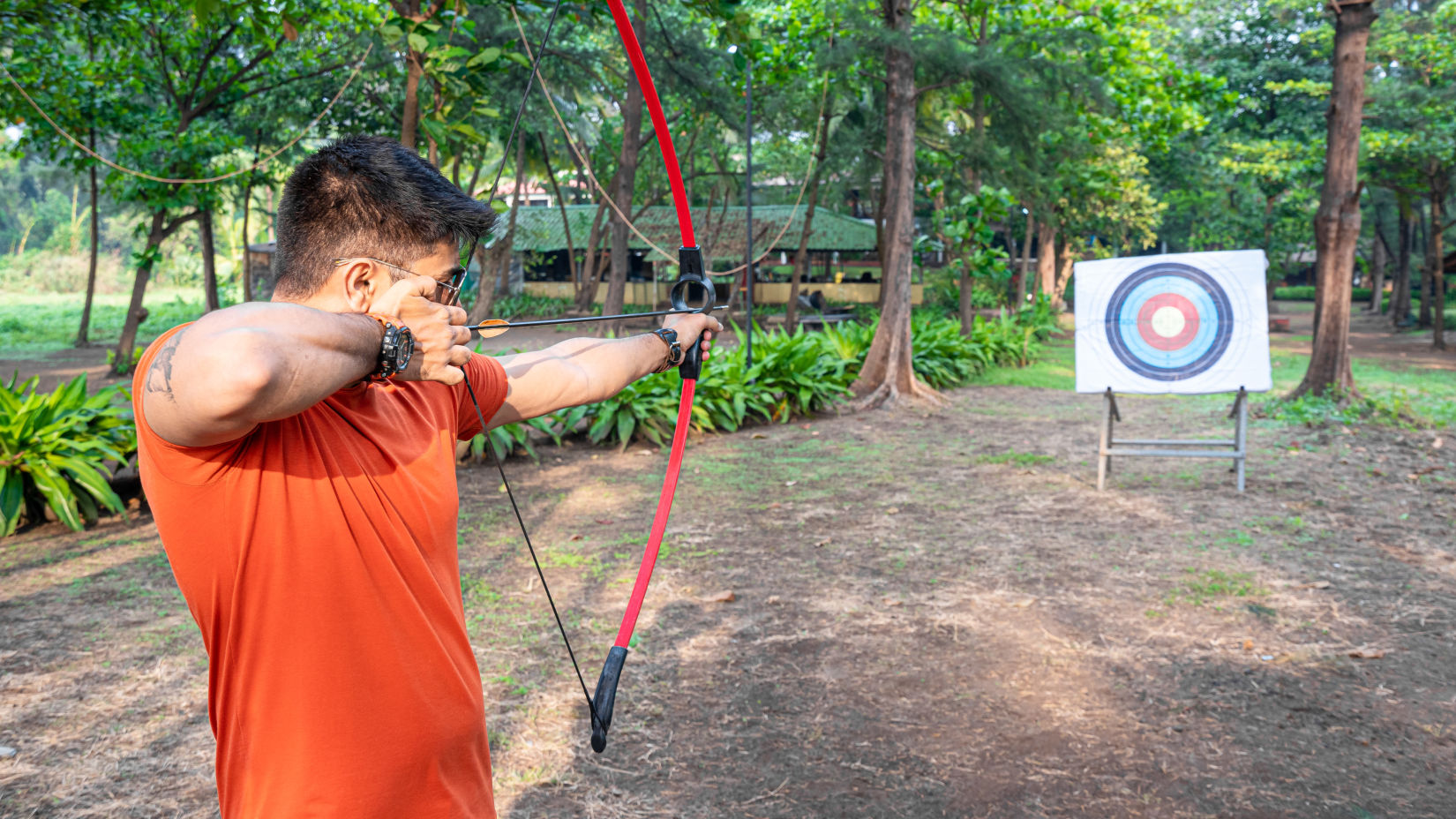 A man with a bow and arrow, aiming at the target