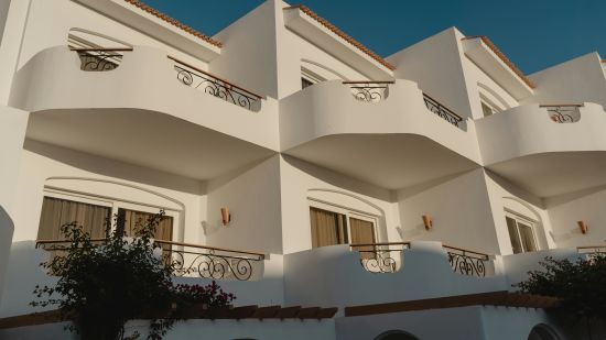 A close-up of a white Mediterranean-style villa with decorative iron railings and terracotta roof tiles