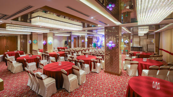 Side view of Blossom hall with stylish decor, lights, and round seating at Icon Premier Hotel by Bhagini, Devarabisanahalli