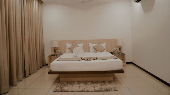 Pride Ranakpur Resort Convention Centre - interior view of the deluxe room featuring an air conditioner a fan and a queen size bed