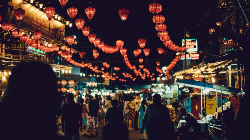 a night market filled with people and decorated with red lantern-looking lights