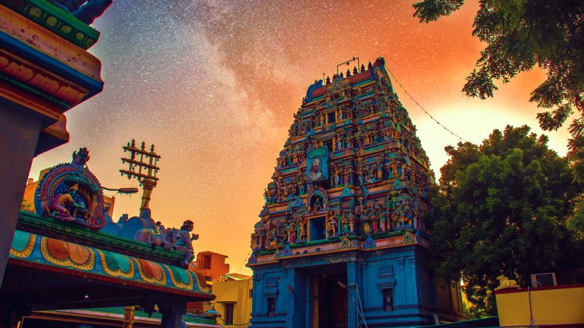 a facade of a temple in india with the sun setting in the background