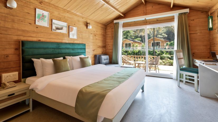 a double bed with pillows on it and entrance to the balcony in view inside one of the rooms - Stone Wood Jungle Resort, Dandeli