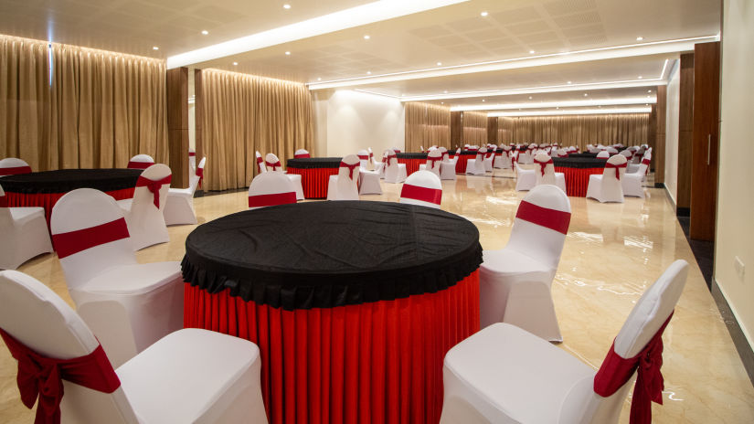 A banquet hall with round tables and white seats - The Residences at CSE