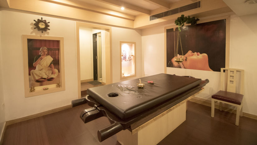 A massage table inside the Spa with a painting hung on the wall- Hotel VITS Aurangabad