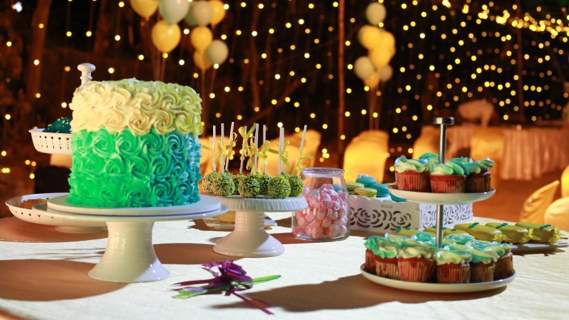 Birthday cake and other cupcakes set on a table with led lights in the background