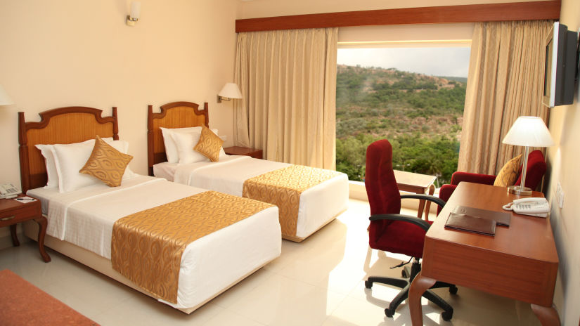 twin beds with a study table in front of it in superior rooms in Tirupati - Raj Park Hotel, Tirupati